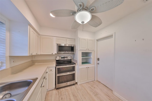 kitchen with stainless steel appliances, light countertops, light wood-style floors, white cabinetry, and a sink