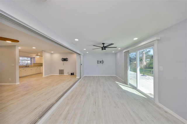 unfurnished living room with a ceiling fan, light wood-style floors, and baseboards