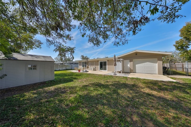 view of yard with a storage shed, an attached garage, fence, an outdoor structure, and a patio area