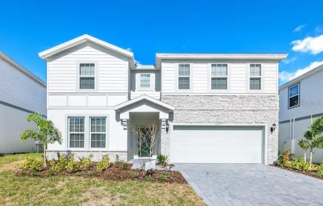 view of front of house with stone siding, an attached garage, and driveway