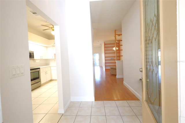 hall featuring light tile patterned flooring and baseboards