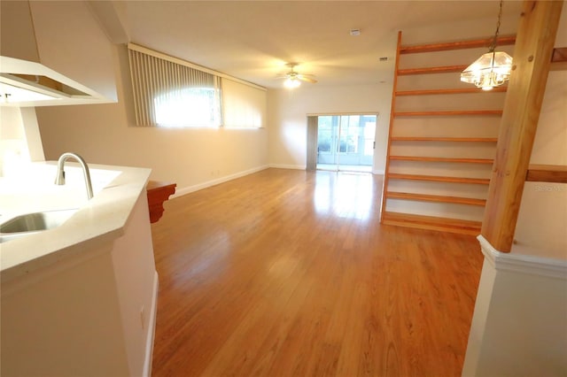 interior space with baseboards, a sink, light wood-style flooring, and a ceiling fan