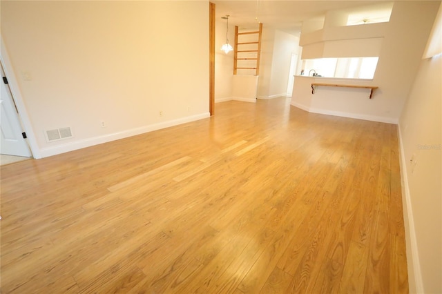 unfurnished living room with light wood-type flooring, visible vents, and baseboards