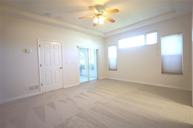 empty room featuring carpet floors, a raised ceiling, and visible vents