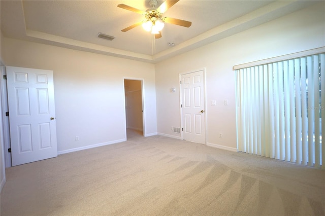 unfurnished bedroom featuring visible vents, a tray ceiling, and baseboards