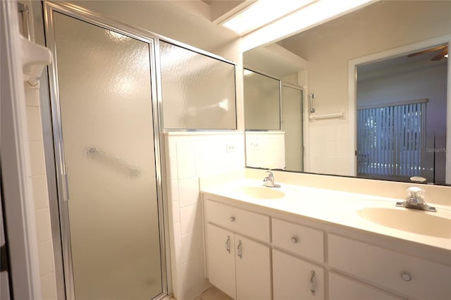 full bath featuring double vanity, a shower stall, and a sink