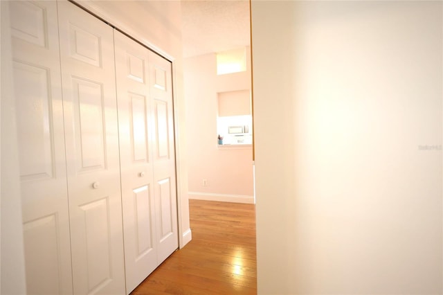 corridor with light wood-style flooring and baseboards