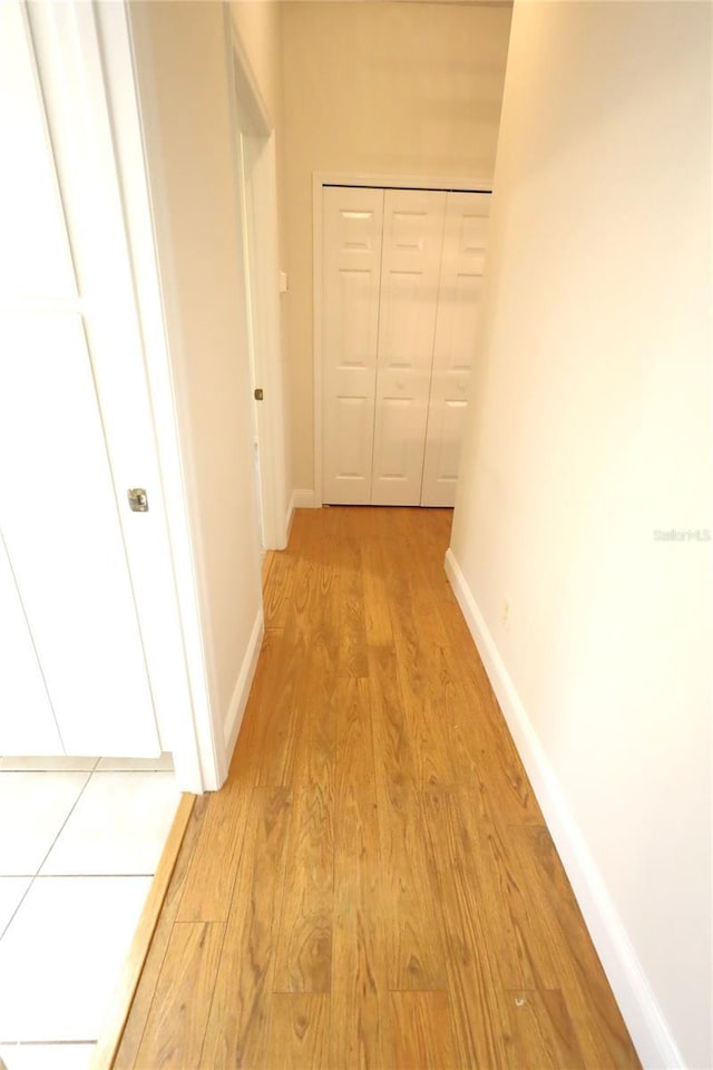 hall with light wood-style floors and baseboards