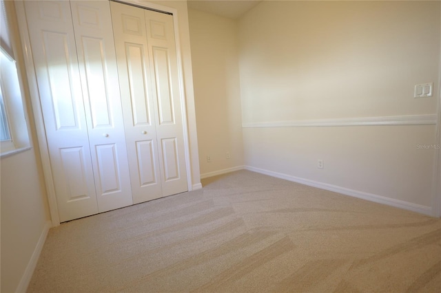 unfurnished bedroom featuring carpet, baseboards, and a closet