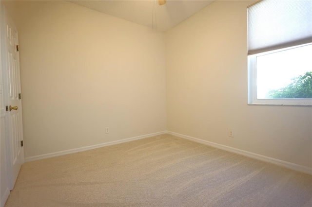 empty room featuring light carpet and baseboards