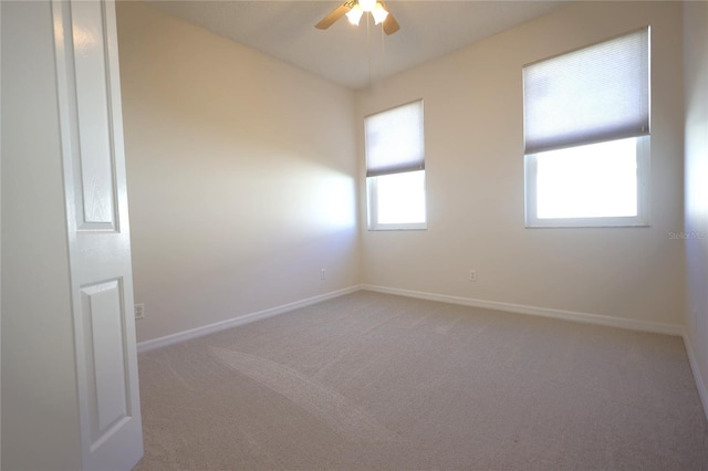 empty room with carpet floors, a ceiling fan, and baseboards