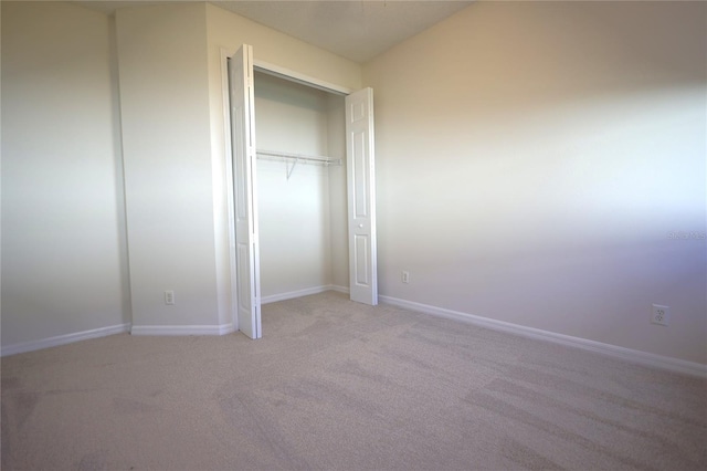 unfurnished bedroom with baseboards, a closet, and light colored carpet