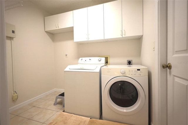 washroom featuring cabinet space, light tile patterned floors, baseboards, and washer and clothes dryer