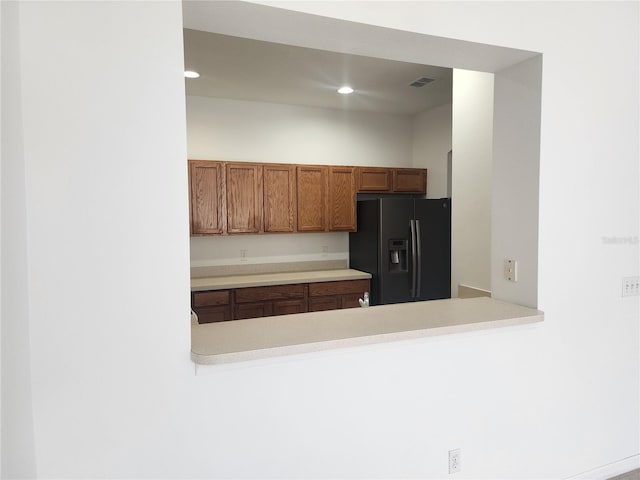 kitchen with recessed lighting, light countertops, black fridge with ice dispenser, visible vents, and brown cabinetry