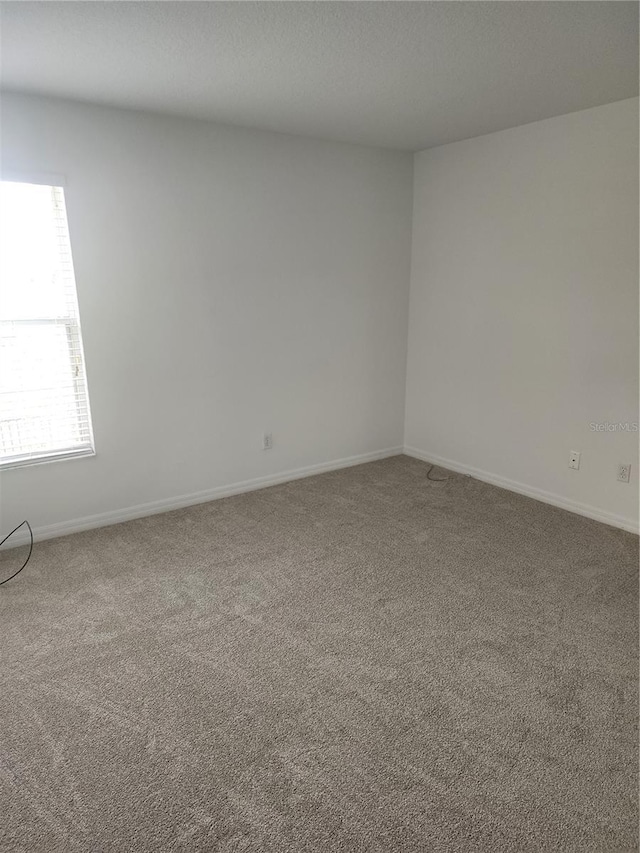 unfurnished room with carpet floors and baseboards