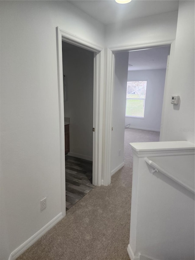 hallway featuring carpet flooring and baseboards