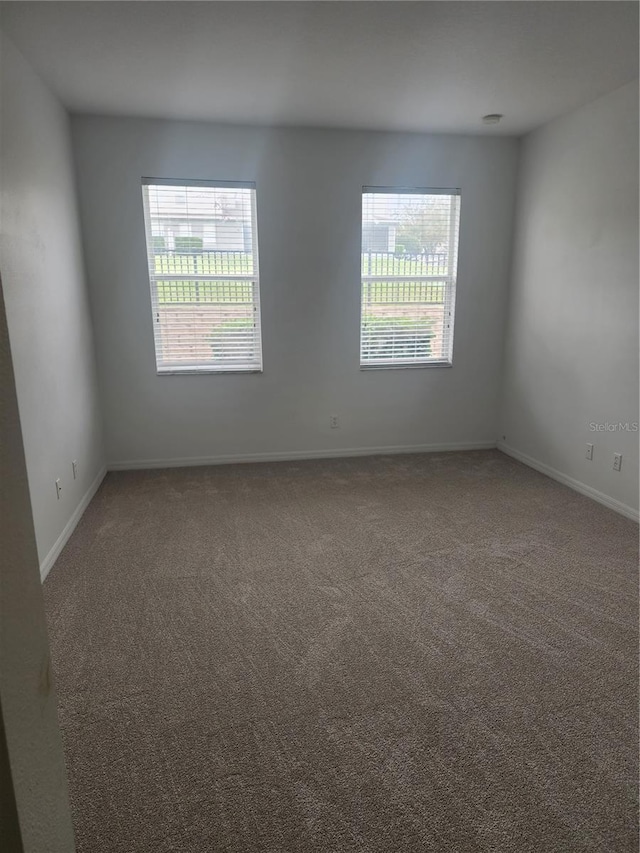 empty room featuring carpet floors, a healthy amount of sunlight, and baseboards