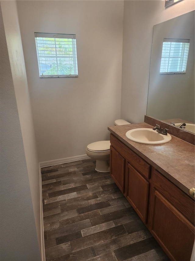 bathroom featuring a healthy amount of sunlight, toilet, wood finished floors, and vanity