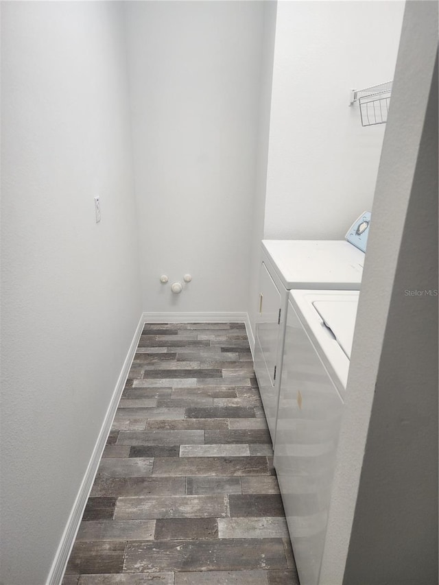 laundry area featuring laundry area, separate washer and dryer, dark wood-type flooring, and baseboards