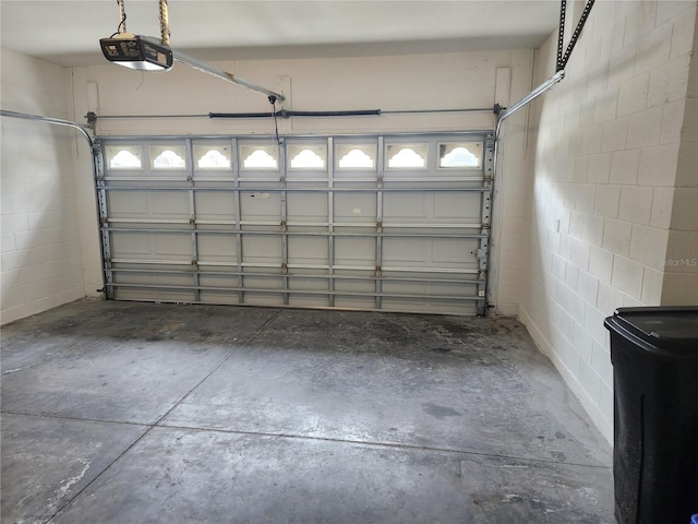 garage with a garage door opener and concrete block wall