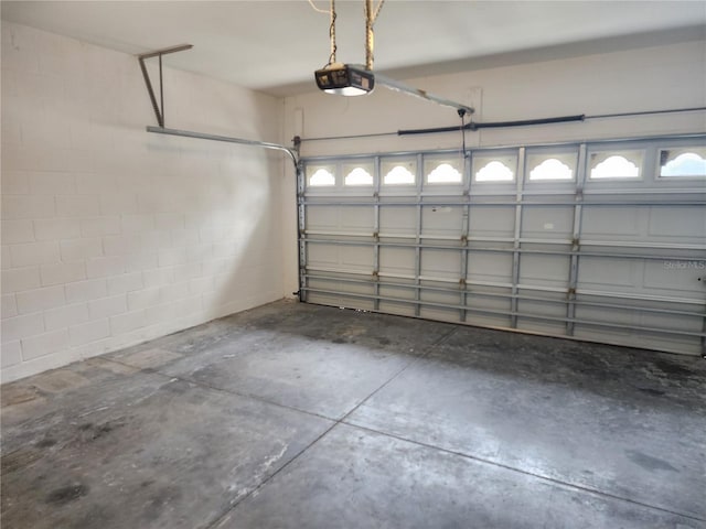 garage featuring a garage door opener and concrete block wall