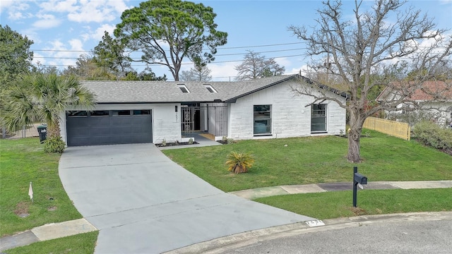 view of front facade featuring driveway, a shingled roof, an attached garage, and a front yard