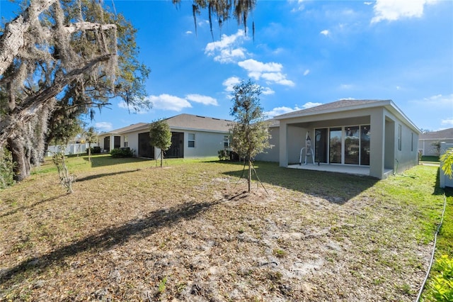 back of property featuring a yard and stucco siding