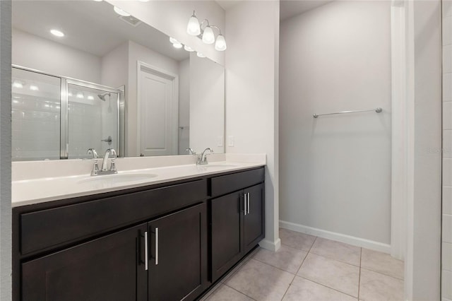 bathroom with double vanity, baseboards, tile patterned flooring, a shower stall, and a sink