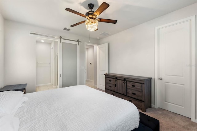 bedroom with light colored carpet, visible vents, ceiling fan, and a barn door