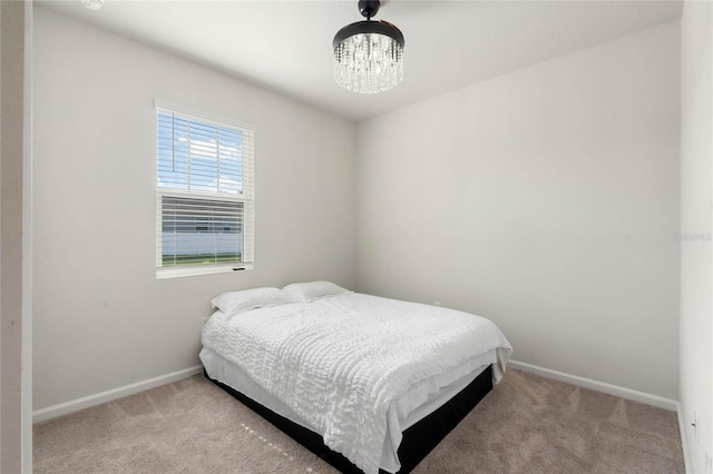 bedroom featuring light colored carpet, baseboards, and an inviting chandelier