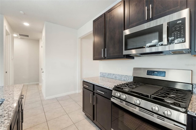 kitchen featuring light tile patterned floors, light stone counters, dark brown cabinetry, stainless steel appliances, and visible vents