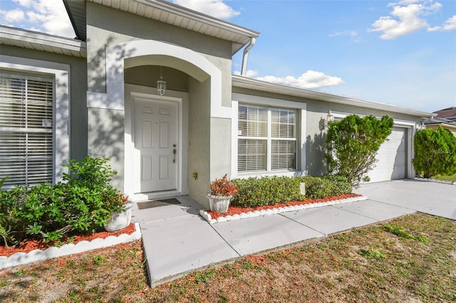 property entrance featuring a garage, driveway, and stucco siding