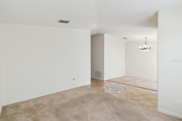 unfurnished room with light colored carpet, a notable chandelier, visible vents, and light tile patterned flooring