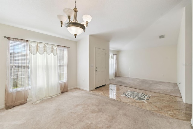 foyer entrance featuring light tile patterned floors, a chandelier, visible vents, and light colored carpet