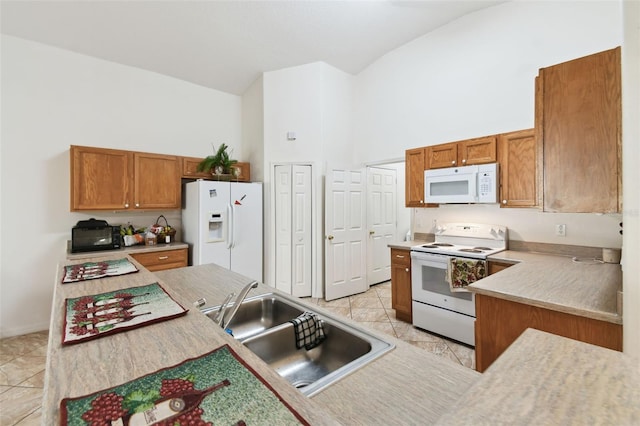 kitchen with white appliances, light countertops, a sink, and brown cabinetry