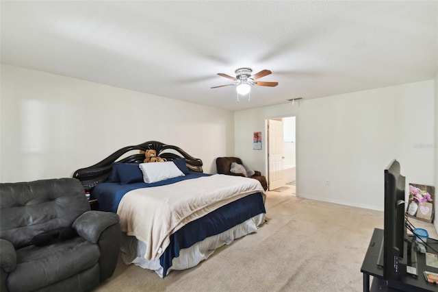 bedroom with baseboards, connected bathroom, a ceiling fan, and light colored carpet