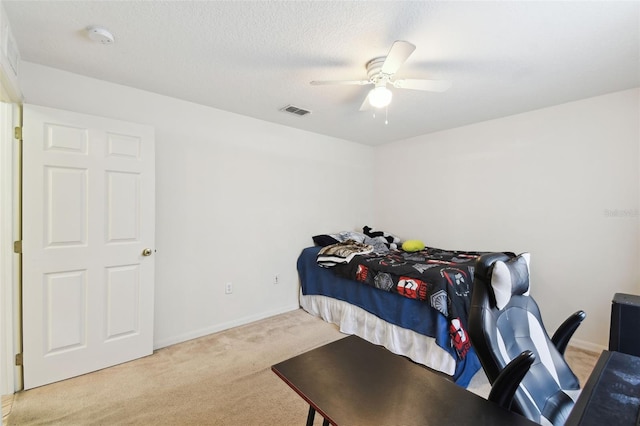 bedroom with visible vents, baseboards, light colored carpet, ceiling fan, and a textured ceiling