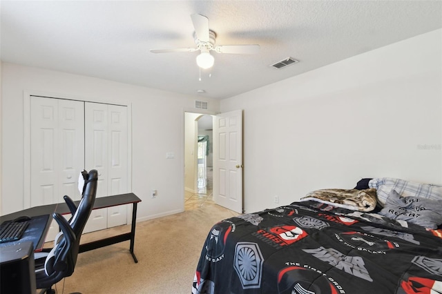 bedroom featuring a closet, visible vents, light carpet, and a textured ceiling