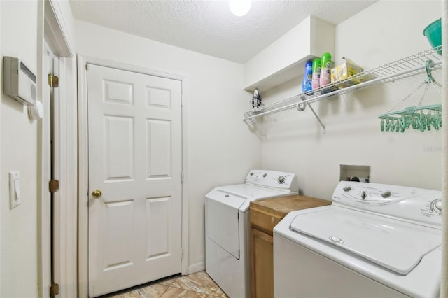 washroom featuring a textured ceiling and washing machine and dryer