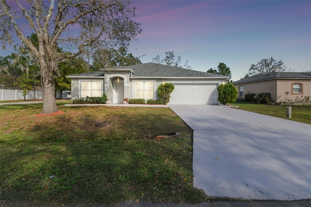 ranch-style home featuring a garage, driveway, a front lawn, and stucco siding