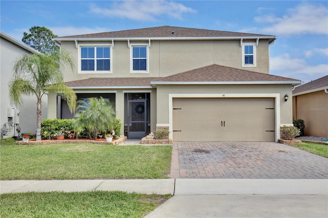 traditional home with a shingled roof, an attached garage, decorative driveway, a front lawn, and stucco siding