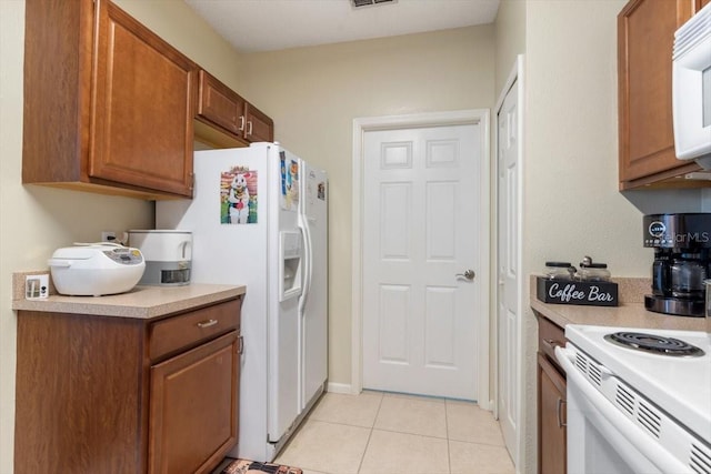 kitchen featuring brown cabinets, white appliances, light tile patterned floors, and light countertops