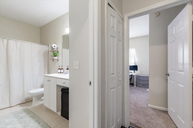 full bath featuring toilet, a shower with curtain, tile patterned floors, vanity, and a closet