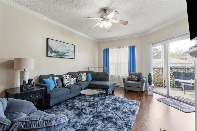 living room with a ceiling fan, a textured ceiling, ornamental molding, and dark wood-type flooring