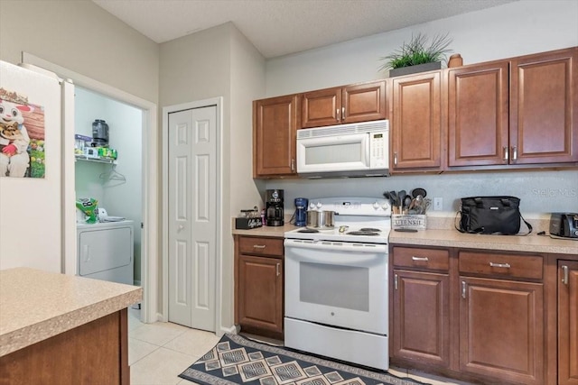 kitchen with light tile patterned floors, white appliances, light countertops, brown cabinets, and washing machine and clothes dryer