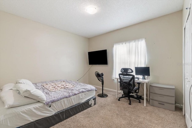 bedroom with baseboards, a textured ceiling, and light colored carpet