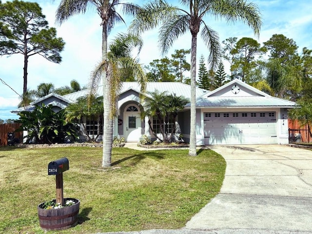 single story home featuring an attached garage, metal roof, a front lawn, and concrete driveway