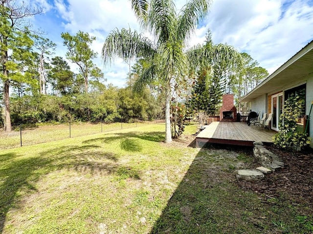 view of yard featuring a deck, an outdoor fireplace, and a fenced backyard