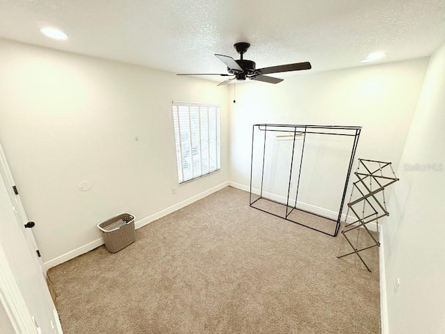 unfurnished bedroom with ceiling fan, baseboards, a textured ceiling, and light colored carpet