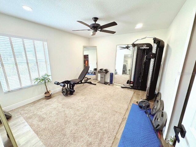 exercise area with a textured ceiling, ceiling fan, recessed lighting, wood finished floors, and baseboards